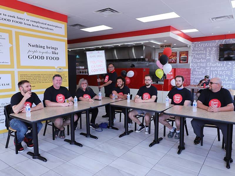 Ten minutes before the whistle at the 2024 poutine eating contest: every seat taken, contestants in Sam's Grill shirts, nobody eating yet.