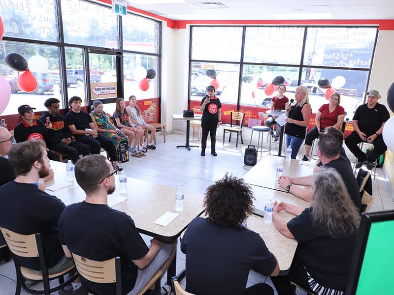 The room before the first plate — the host on the microphone and every chair around the tables full.